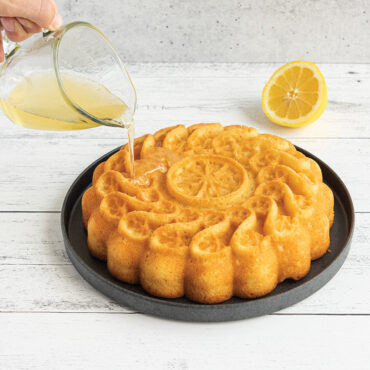 A delicious citrus twist cake on a plate. A honey glaze is being poured on top of cake, action shot.