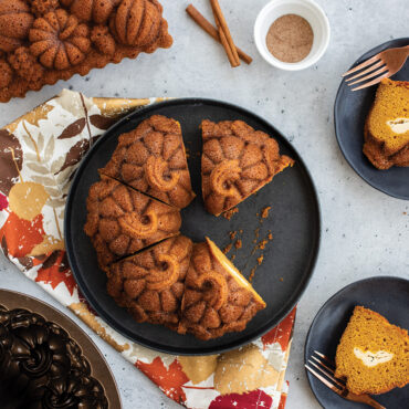 The image showcases a stunning overhead view of the Pumpkin Patch Bundt cake cut a long with a fall loaf cake in a group baking scene.