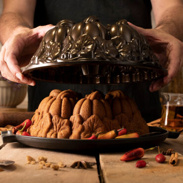 The image depicts a person unveiling  the pumpkin patch cake from the Pumpkin Patch Bundt Pan.