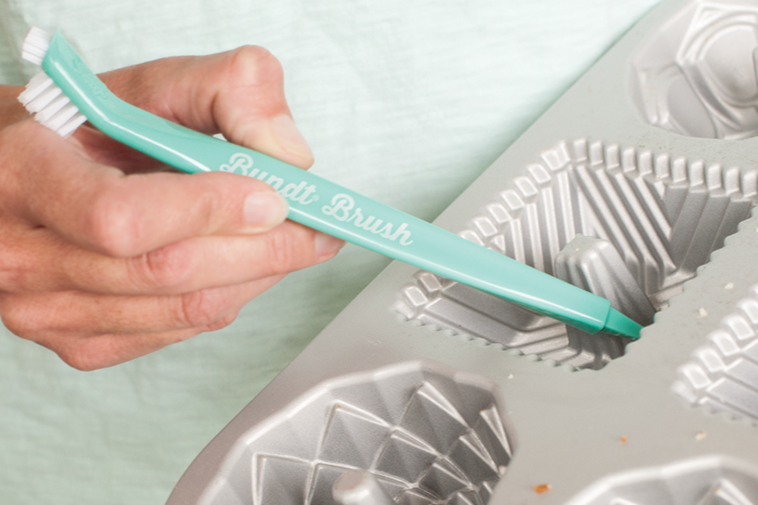 Bundt cleaning tool being used to remove cake debris from a Bundt pan. 