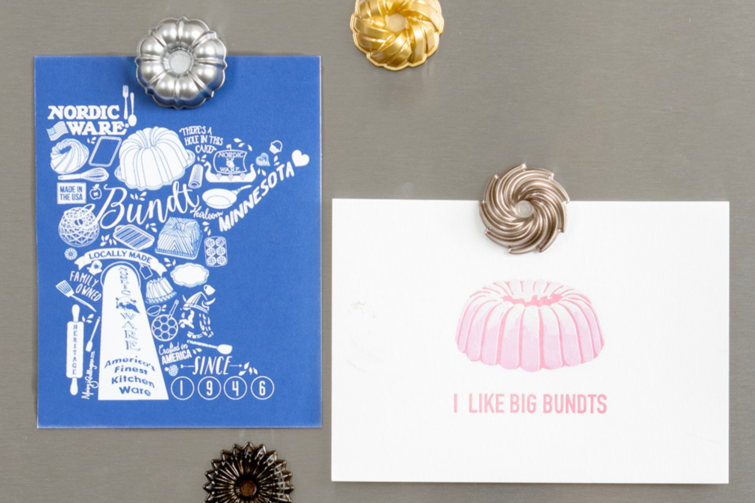 Cute Nordic Ware themed cards hanging on a refrigerator using Bundt magnets. 