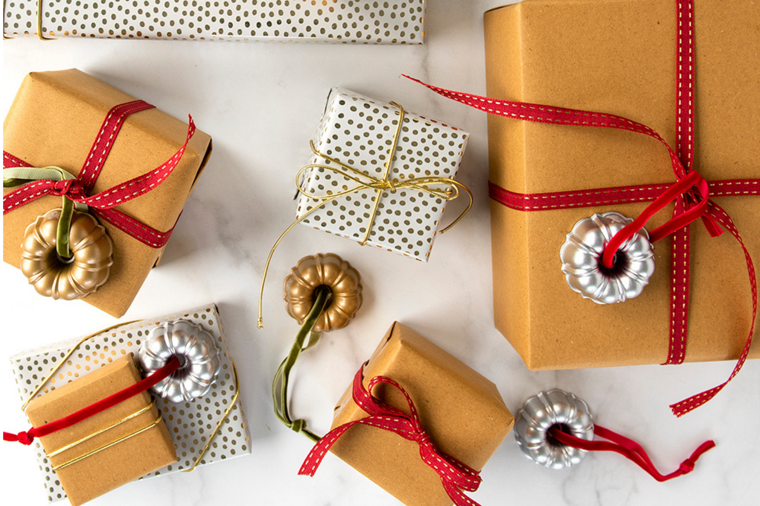 Presents wrapped and tied with ribbon with Bundt ornaments attached to each gift. 