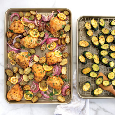 Baked chicken o baking sheet and baked vegetables on baking sheet