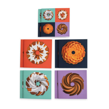 Bundt® Pan Greeting Cards separate by design. Top is design 1 with all four bundt shapes on one card. Top left, is anniversary Bundt design with white glaze on red background. Top right, is gold Jubilee Bundt Pan on navy background. Bottom left is the swirl Bundt with white glaze on a teal background. Bottom right,  heritage Bundt Cake on purple background.