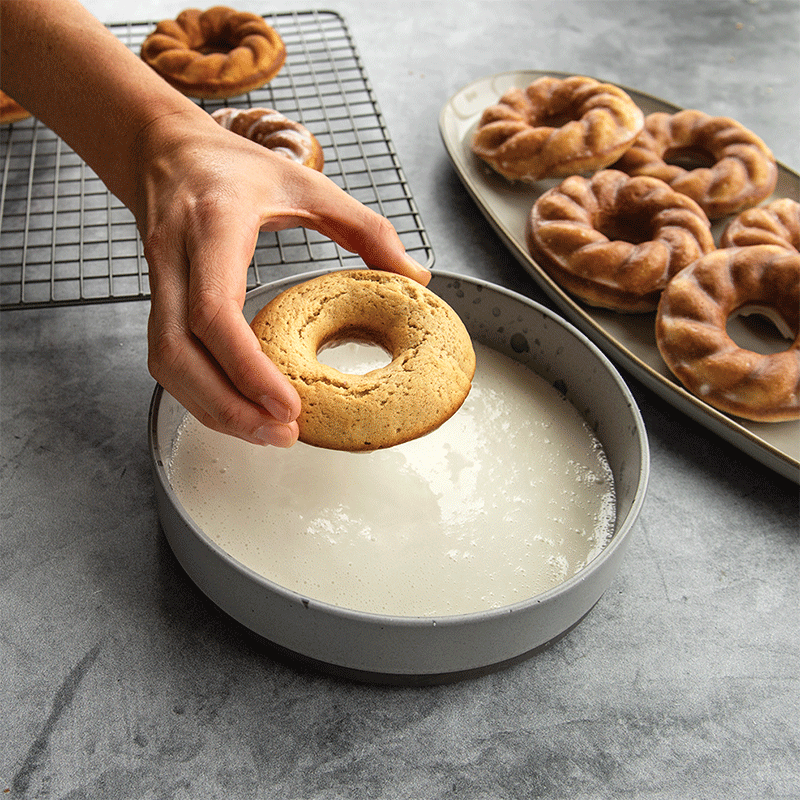 Hand dipping baked twist donuts into glaze- moving GIF