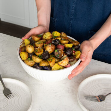 hands holding Nordic Ware 3.5 quart bowl filled with roasted potatoes