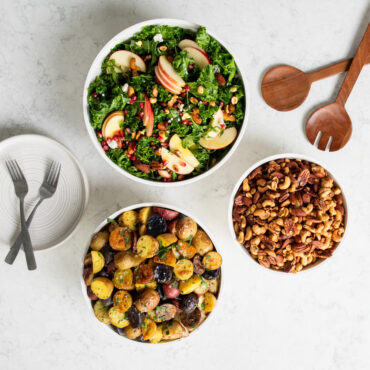 Nordic Ware 3 piece white prep and serve 5 quart, 3.5 quart and 2 quart bowls on kitchen countertop filled with salad, potatoes, and mixed nuts