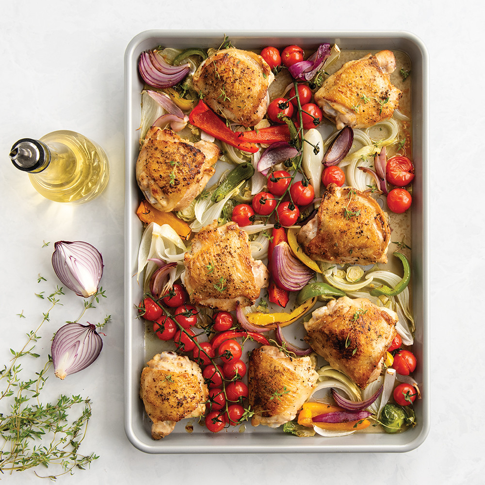 Roasted chicken thighs and colorful vegetables on Nordic Ware Brilliant aluminum half sheet pan, golden brown