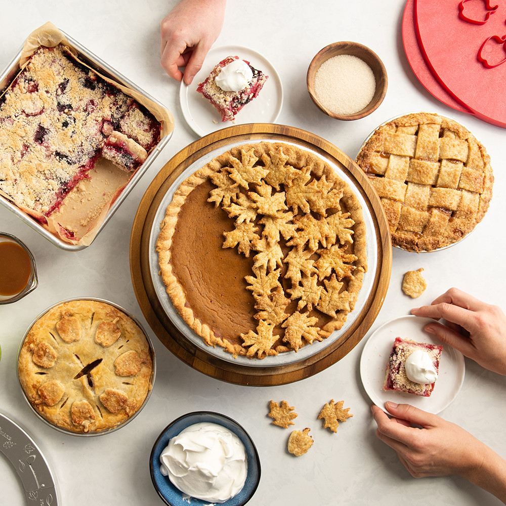 Overhead image of pie dessert table including a pumpkin pie, mini apple pies and bars.