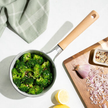 Nordic Ware 1.5-quart cardamom ceramic nonstick saucepan with steamed broccoli, overhead view with cutting board
