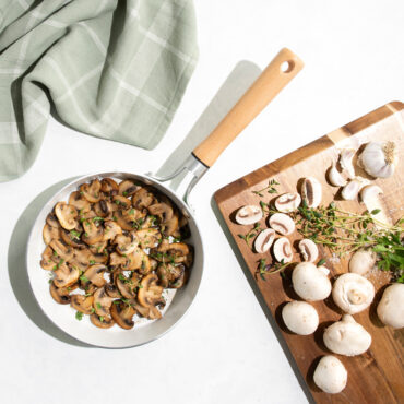 Nordic Ware 8-inch cardamom ceramic nonstick skillet with sautéed mushrooms, overhead view with cutting board