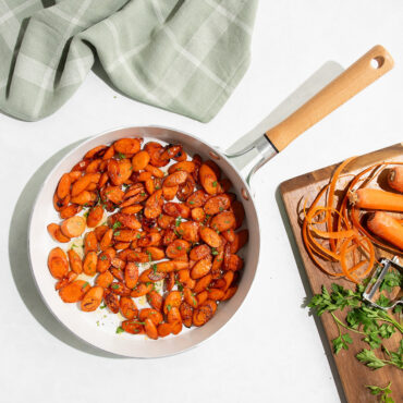Nordic Ware Cardamom ceramic nonstick 10-inch skillet with diced orange carrots, cutting board with whole carrots