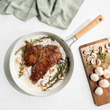 Nordic Ware cardamom ceramic nonstick 12-inch skillet with seared steak, mushrooms on cutting board nearby