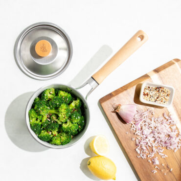 Overhead image of Cardamom 1.5Qt Saucepan with broccoli in pan, lid next to pan, cutting board with chopped ingredients