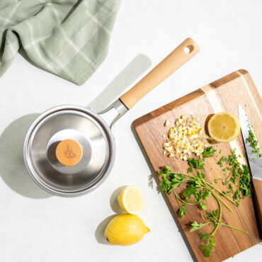 Overhead image of Cardamom 1.5Qt Saucepan with lid, cutting board with chopped ingredients