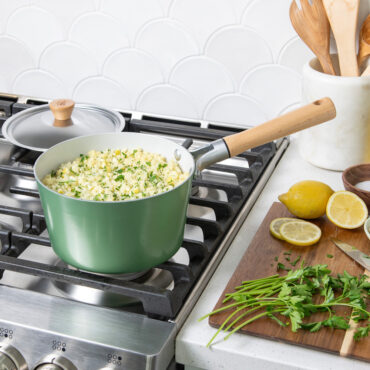 Nordic Ware cardamom-colored 3-quart saucepan on stovetop with cooked rice, lid beside pan, ingredients on cutting board
