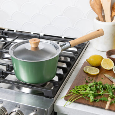 Nordic Ware cardamom-colored 3-quart saucepan with lid on stovetop, cutting board with fresh ingredients nearby