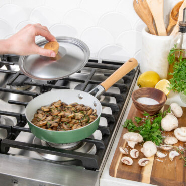 Nordic Ware Cardamom 8-inch nonstick saute pan with lid being placed on top, containing sauteed mushrooms
