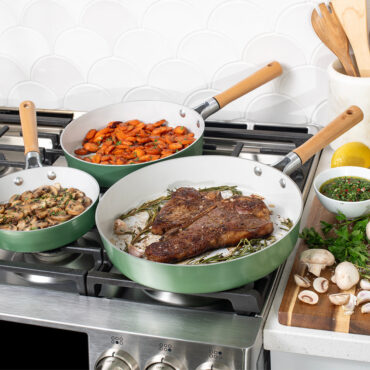 Image of Cardamom 3 piece fry pans on stovetop with steak, carrots and mushrooms in pans