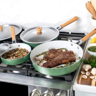 Cardamom 6 piece fry pan and lid set on stovetop, steak, carrots and mushrooms in pans