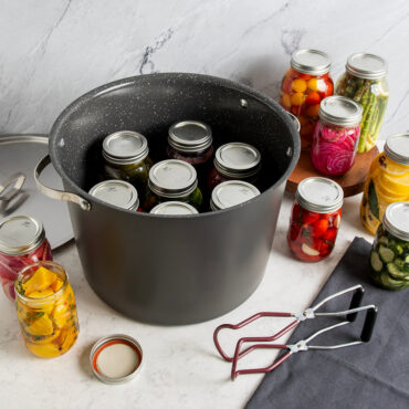 20 Qt Stock Pot with lid displayed with various jars of vegetables inside of stock pot