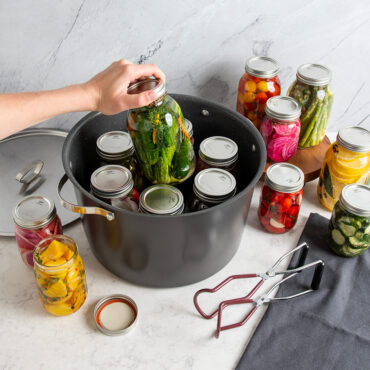16qt Stock Pot with Lid; hand placing jars of vegetables into stock pot