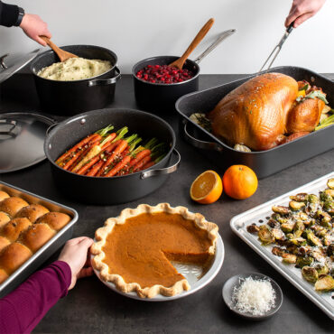 Thanksgiving group table shot with hands serving from different pans for food
