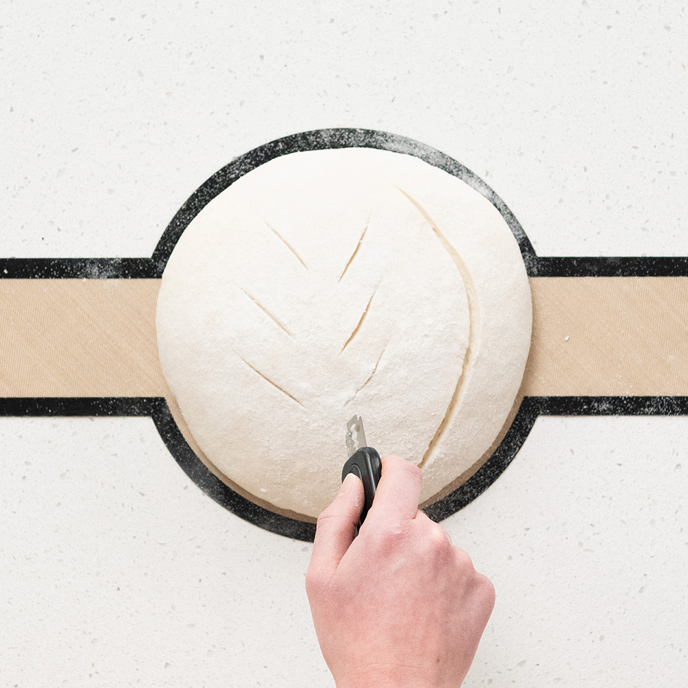 Image of scouring sourdough loaf with lame in overhead shot