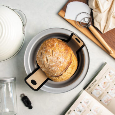 Over head image of baked sourdough bread in Nordic Ware's Bread Baking Pan with tools in kit around it.