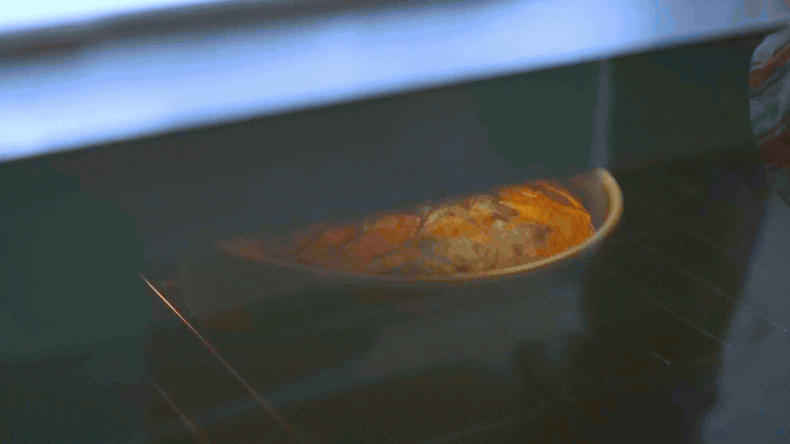 Hand taking a perfectly baked marbled cake out of the oven. 