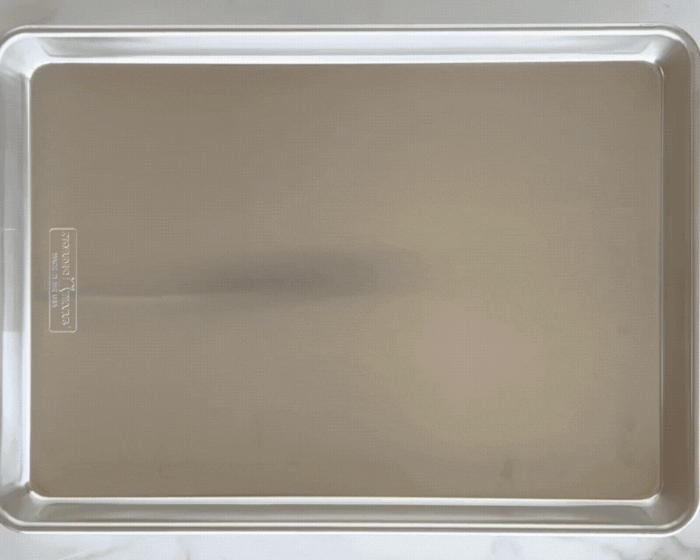 Gif of baked Ham and Cheese Sliders being assembled the Naturals® Big Batch Pan. Beginning with buns, then mayo, then cheese, then turkey, then the tops of the buns, then a pour over of melted butter. 