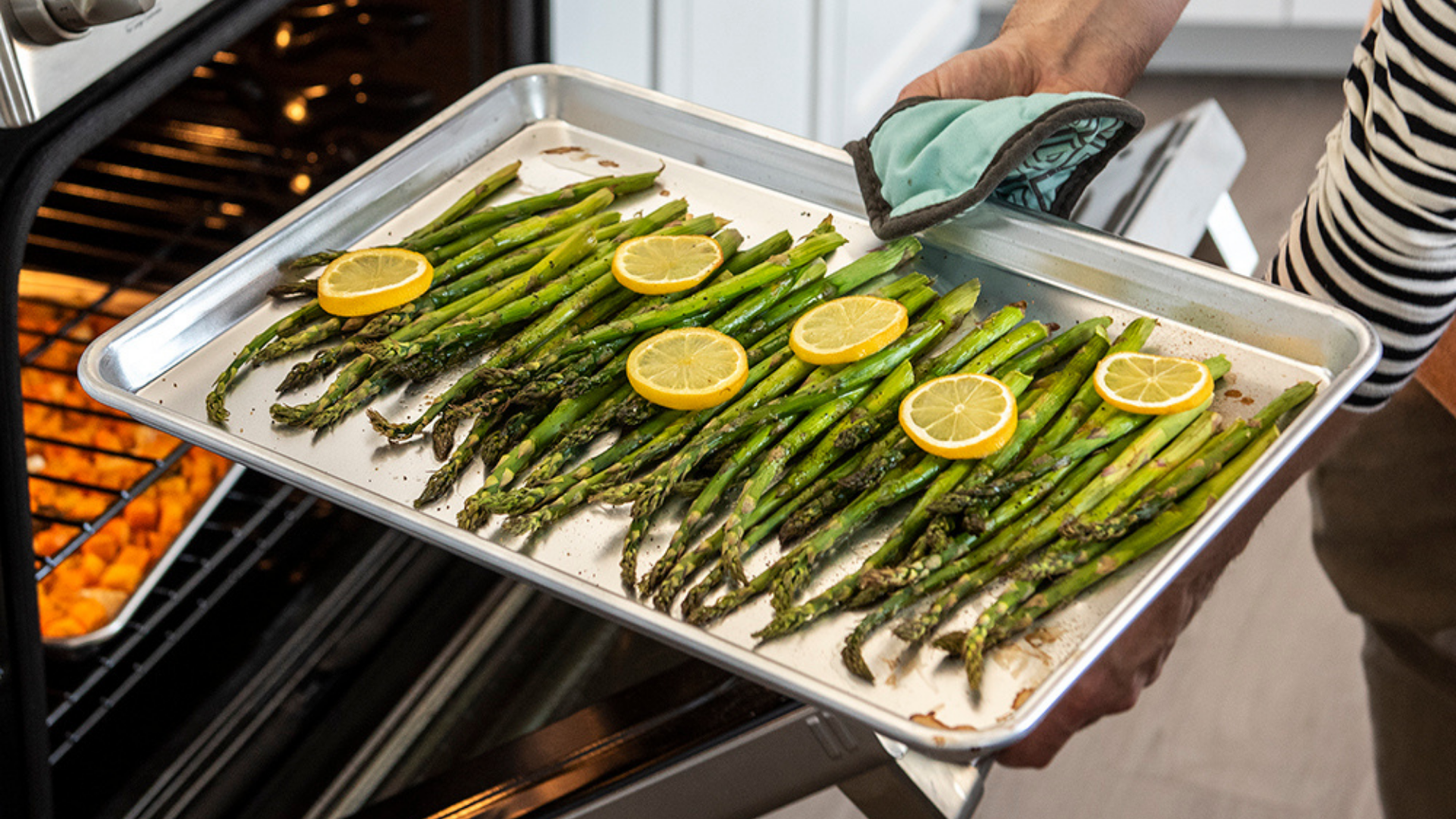 Roasted asparagus on a Naturals Aluminum Baking Sheet being removed from the oven. 