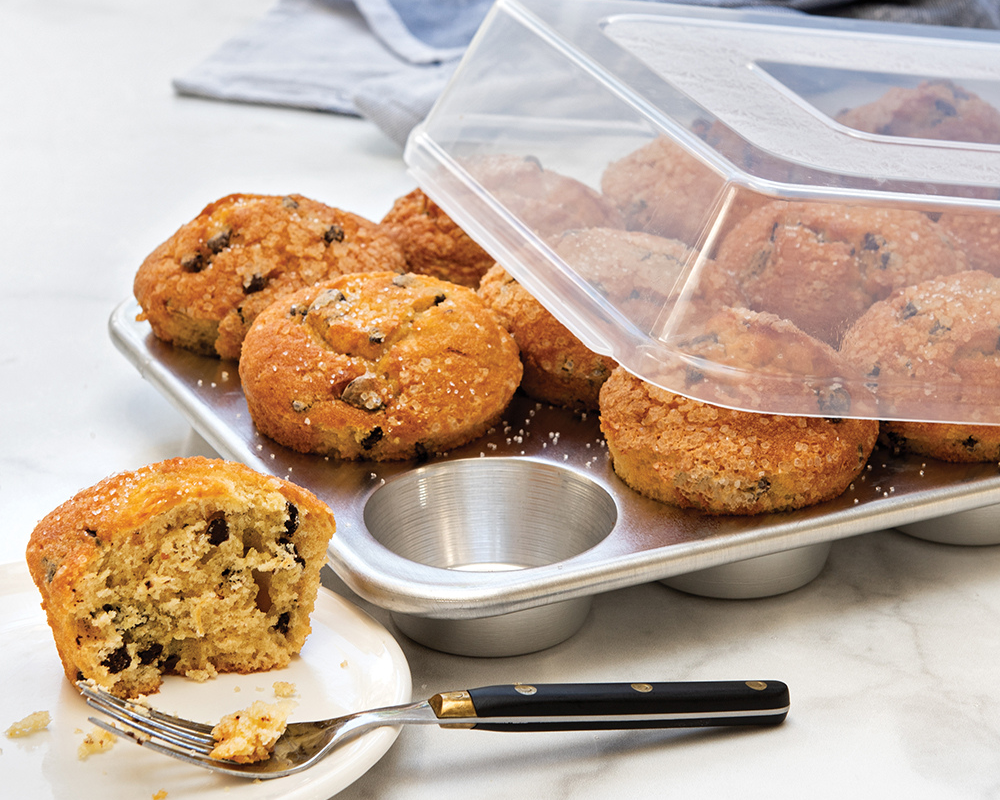 12-cavity Naturals® Muffins Pan filled with chocolate chip muffins being covered with a lid.