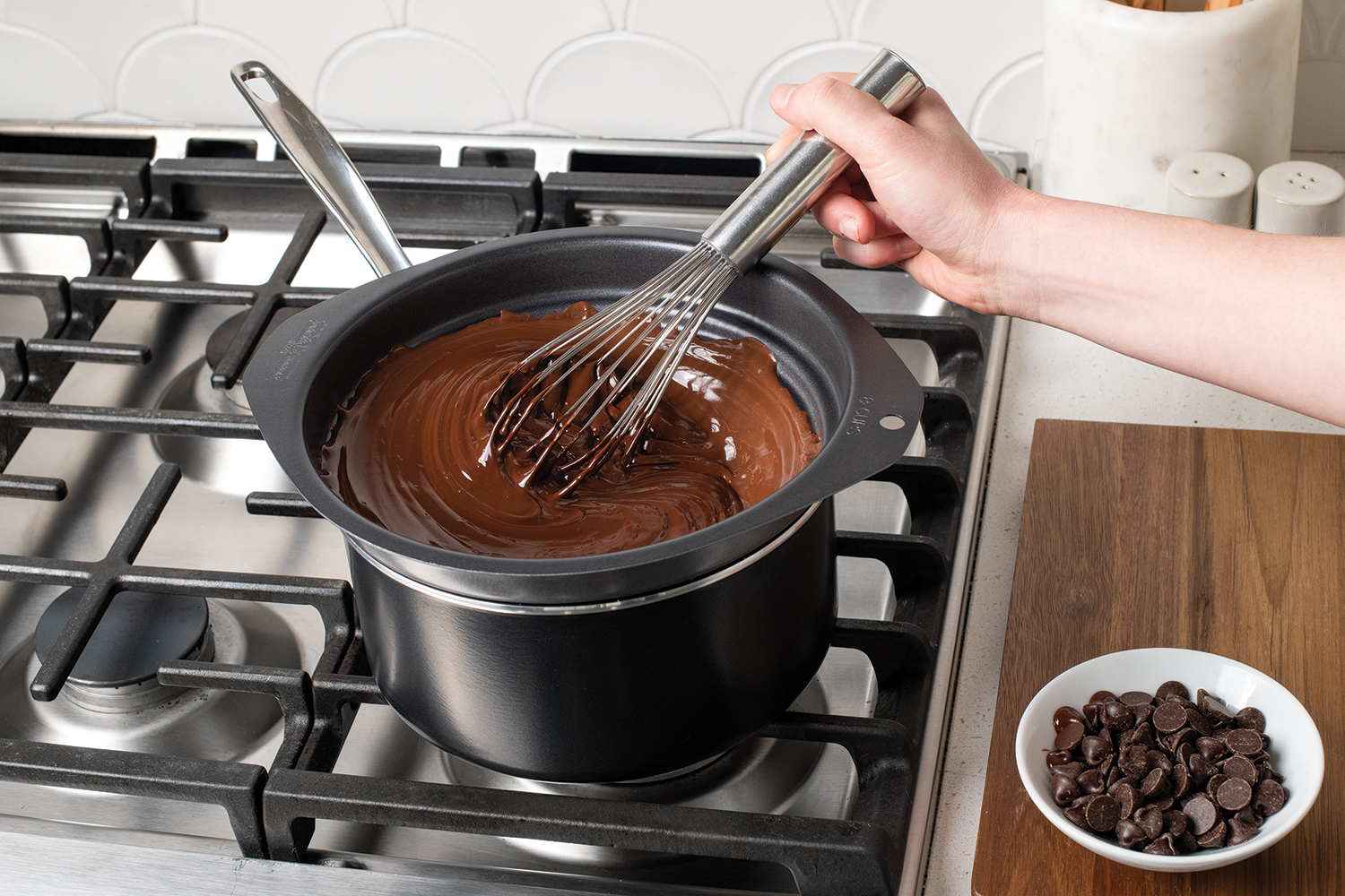 Hand mixing melted chocolate in the Nonstick Universal Double Boiler with a whisk.