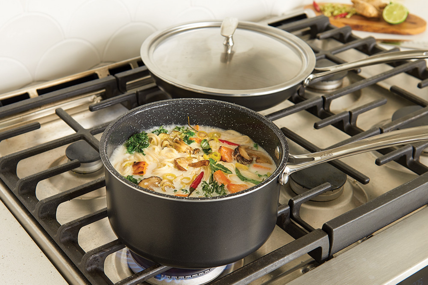 Basalt 3 Piece 8 Inch Sauté Skillet and 3 Qt Sauce Pan with Lid on the stovetop with some soup in the sauce pan.