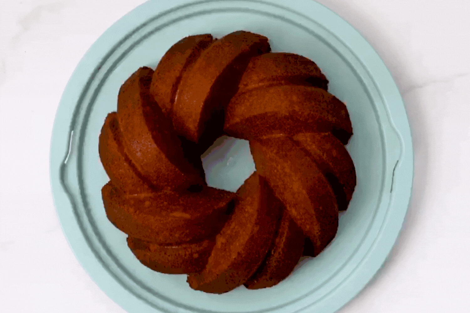 Translucent Bundt® Cake Keeper Putting the lid of the Translucent Bundt® Cake Keeper on the base and transporting a 75th Anniversary Braided Bundt® Cake.