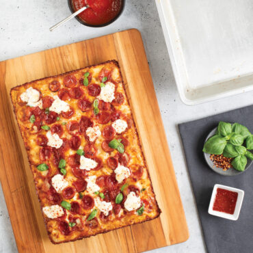 Pizza placed on cutting board next to pan