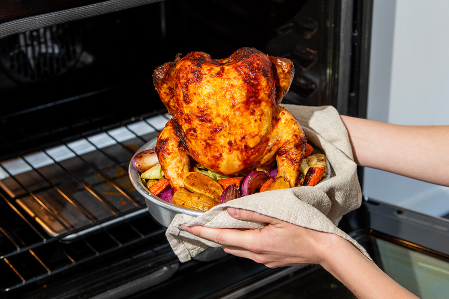 One Pan Roasted Whole Chicken and Veggies coming out of the oven on the Vertical Chicken Roaster.