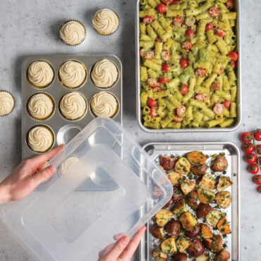 overhead view of naturals 5 piece bakeware set with cupcakes in muffin pan, noodle casserole in rectangular baking pan, and potatoes on multi rack and quarter sheet
