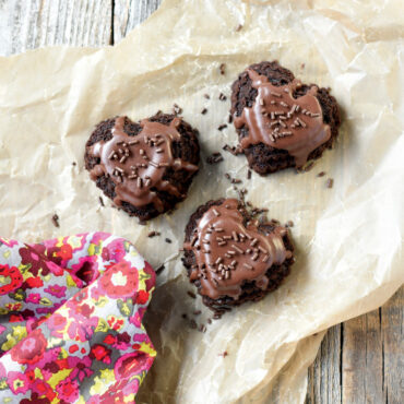 Chocolate Heart Cakelets with chocolate frosting and sprinkles on parchment paper