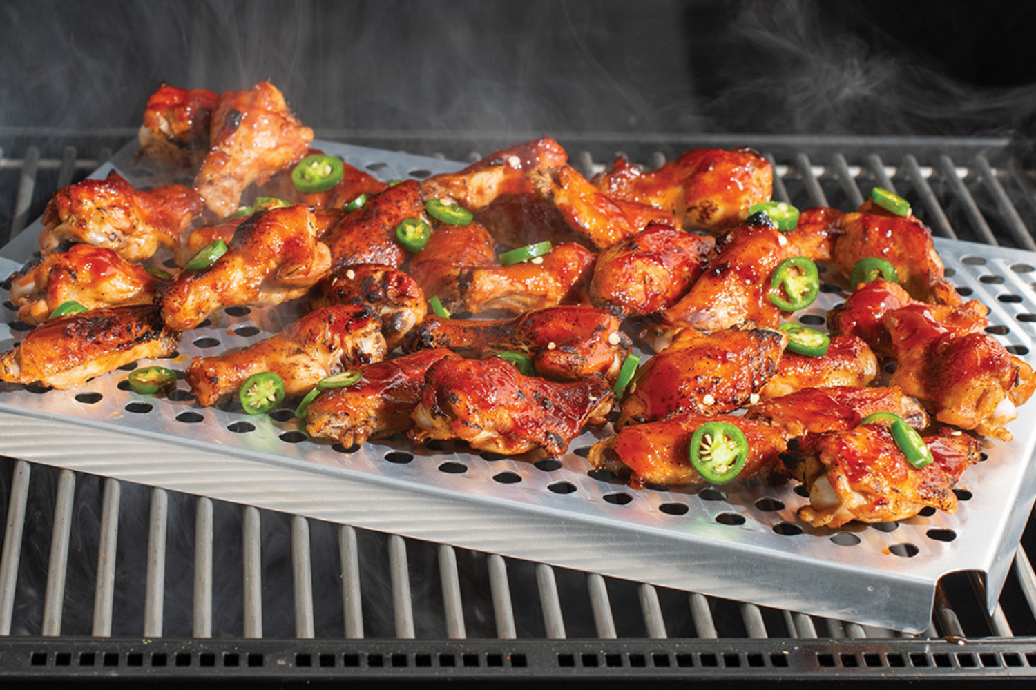Spicey BBQ chicken wings cooking on the grill on the Multi-Purpose Oven & Cooling Rack.