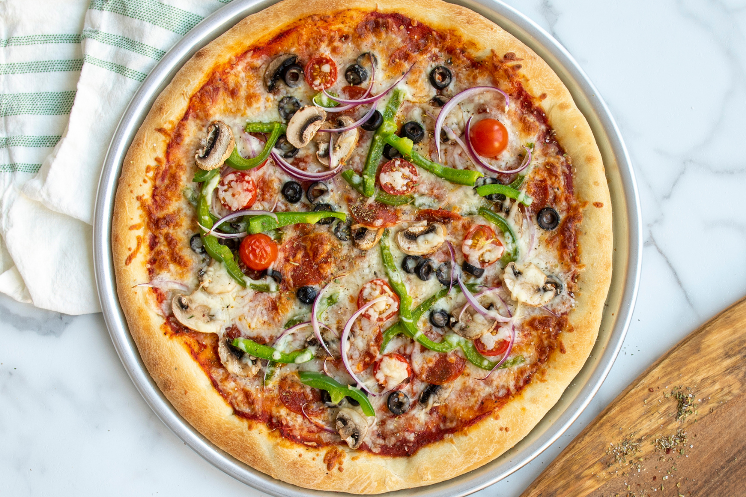 Naturals® Traditional Pizza Pan with supreme pizza baked on it. 