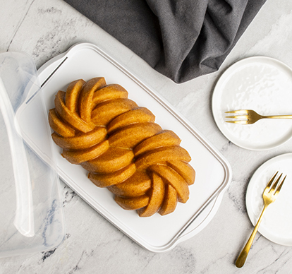 Image of baked Braided Loaf Cake in Nordic Ware white loaf cake keeper.