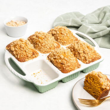 aluminum mini loaf pan with 8 rectangular cavities filled with cakes, one cake plated