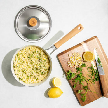 overhead view of cardamom 3.5qt saucepan with rice, lid next to it with cutting board of ingredients