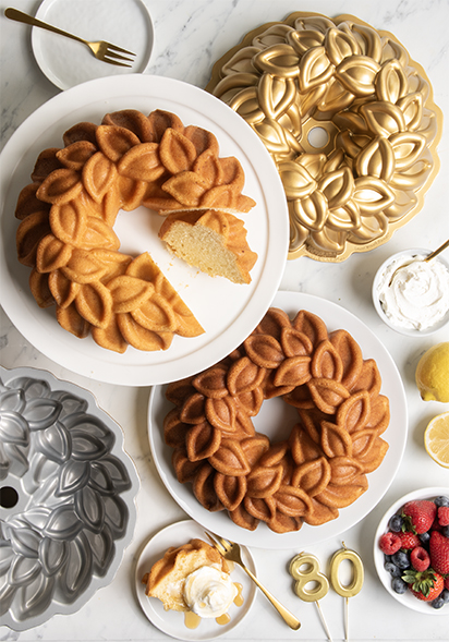 Image of two baked Laurel Wreath Bundt cakes with pans and ingredients in celebratory display. 