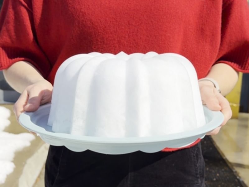 Image of a person holding a cake plate with a molded snow Bundt using Nordic Ware Original Bundt Pan