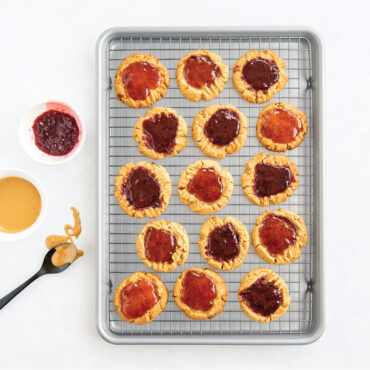 overhead of pb&j cookies on brilliant half sheet with grid