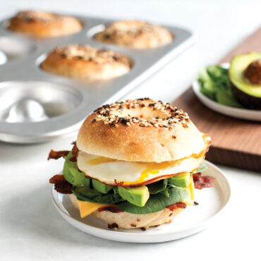 plated egg bagel sandwich with sourdough bagel pan and cutting board in background