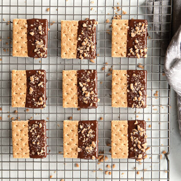 Chocolate-dipped shortbread cookies cooling on Nordic Ware nonstick cooling grid over aluminum sheet pan